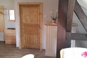 A room with a wooden door, a cabinet, a chair, and a potted plant. - Holiday apartment with 2 bedrooms (Lübben\/Spreewald)