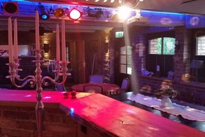 A bar area with a wooden counter, candelabras, and a brick wall. - Holiday apartment with 2 bedrooms (Lübben\/Spreewald)