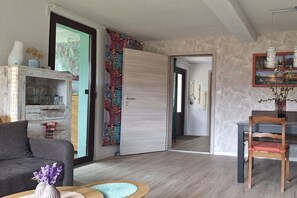 Ein modernes Wohnzimmer mit einer Couch, einem Couchtisch, einem Kamin, einer Essecke mit einem Stuhl und einer Tür zu einem weiteren Raum.