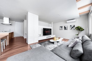 Ein modernes Wohnzimmer mit einer Couch, einem Couchtisch und einem Fernseher.