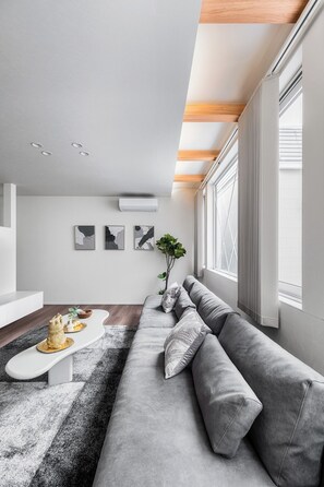 Uma sala de estar moderna com um sofá cinzento, uma mesa de centro branca e arte abstrata nas paredes.