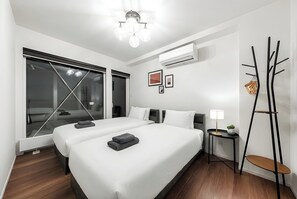 Quarto de hotel moderno com uma cama grande, uma escrivaninha, uma cadeira e vista pela janela.
