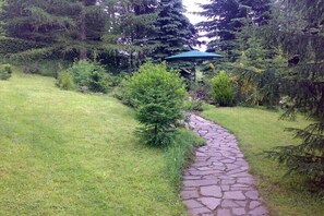 Ein gepflasterter Weg in einem Garten mit verschiedenen Pflanzen und Bäumen.