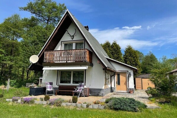 Ett tvåvåningshus med en balkong, en satellantenn och en träveranda.