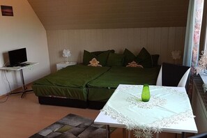 Ein Schlafzimmer mit einem Bett, einem Nachttisch mit Lampe, einem Fernseher und einem Tisch mit einer Vase.