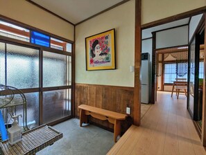 Ein Zimmer mit einer Holzbänkl, einem gerahmten Kunstwerk, einem Fenster mit Blick und einem gefliesten Boden.