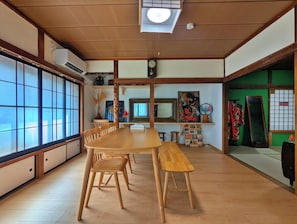 A traditional Japanese-style room with tatami flooring, a wooden dining table with benches, a large shoji screen, and a ceiling fan.