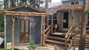Une petite cabane avec un porche en bois, une porte et une fenêtre.