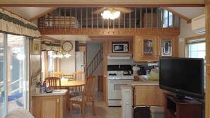Une cuisine compacte avec un coin repas, un téléviseur et un escalier menant à un niveau supérieur.