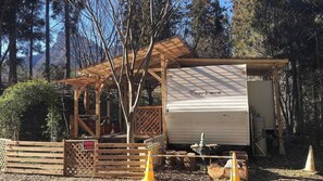 Une structure en bois abritant un parc pour véhicules récréatifs, avec une zone couverte et un grand véhicule récréatif.