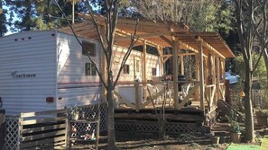 Une maison mobile dotée d’une terrasse en bois et d’un porche abrité.