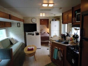 Une cuisine compacte pour camping-car, équipée d’un réfrigérateur, d’une cuisinière et d’un petit coin repas.