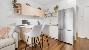 A modern kitchen with a built-in microwave, a stainless steel refrigerator, and a white countertop. - Courtyard 1-Bed Apartment in New Farm (New Farm)