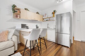 A modern kitchen with a built-in microwave, a stainless steel refrigerator, and a white countertop. - Courtyard 1-Bed Apartment in New Farm (New Farm)