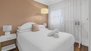 A hotel room with a bed, a nightstand, a lamp, a ceiling fan, and a window with curtains. - Courtyard 1-Bed Apartment in New Farm (New Farm)