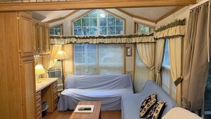 Una habitación acogedora con sofá, mesa, lámpara y ventana con cortinas.