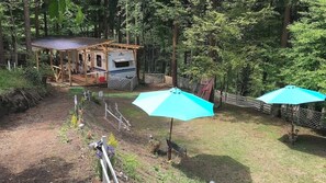 Een camping met een caravan, twee parasols en een houten terras.