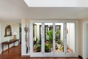 A hallway with a glass door leading to a balcony with potted plants. - Charming Andalusian style Cortijo in La Reserva de Sotogrande (AN)