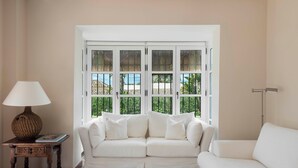 Ein weißes Sofa, eine Lampe und ein Fenster mit Blick auf Grünflächen.