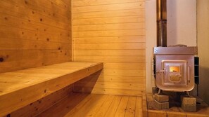 Un sauna en bois, Ă©quipĂ© dâun banc et dâun poĂȘle Ă bois.