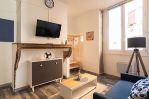 Una habitación con televisión, escritorio, cama, ventana y lámpara.