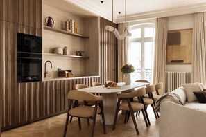 Eine moderne Küche mit einer zentralen Kochinsel, integrierten Regalen und einem Essbereich mit Stühlen.