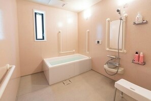 Une salle de bain avec une baignoire, une douche, un lavabo et une fenĂȘtre.