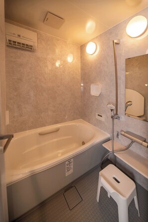 Une salle de bain moderne équipée d’une baignoire, d’une douche, de toilettes et d’un lavabo.