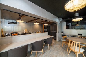 Une cuisine moderne dotée d’un îlot central, de luminaires suspendus et d’un coin repas avec des chaises en bois.