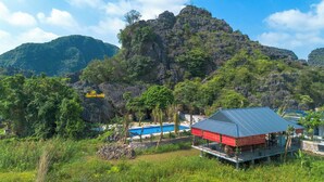Un resort con piscina, un edificio rojo y montañas al fondo.