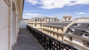 Ein Balkon mit Blick auf historische Gebäude und einen klaren Himmel.