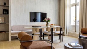 Ein modernes Wohnzimmer mit einem runden Esstisch, beigen Sofas und einem flachbildfernseher an der Wand.
