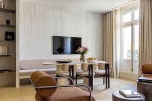 Ein modernes Wohnzimmer mit einem runden Esstisch, beigen Sofas und einem flachbildfernseher an der Wand.