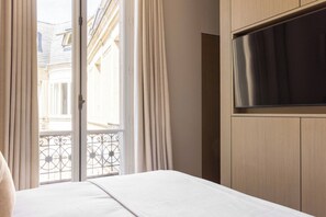 Ein Hotelzimmer mit einem Bett, einem an der Wand befestigten Fernseher und Blick auf den Außenbalkon.