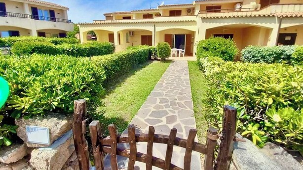 A courtyard with a paved walkway, stone walls, and lush greenery. - Beautiful apartment with sea views (Cannigione)