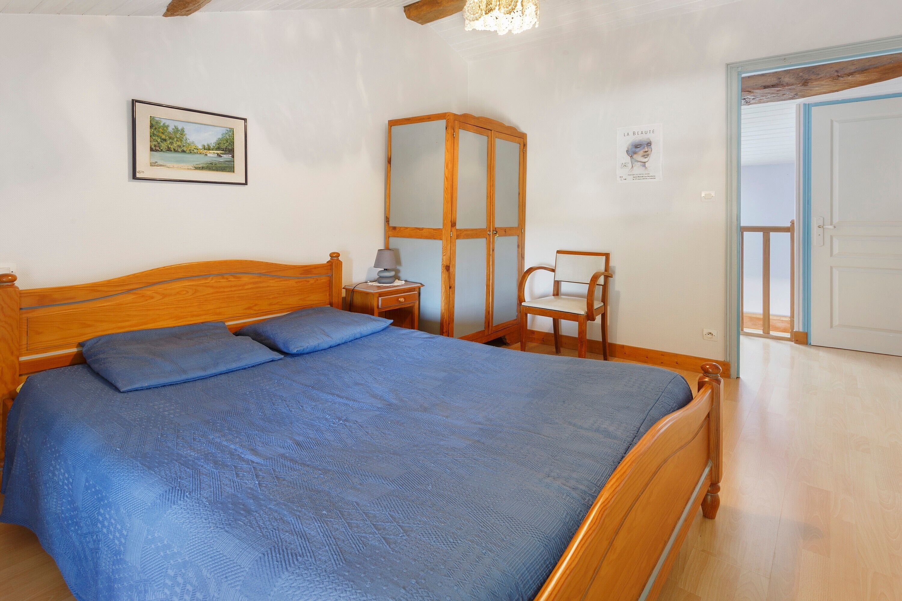 A bedroom with a wooden bed, a nightstand, a chair, and a wardrobe.