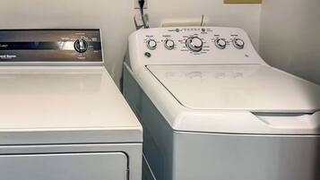 A front view of a laundry room with two washing machines, a water heater, and a power outlet.