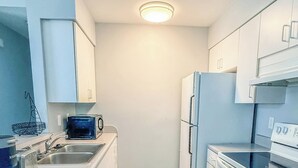 A compact kitchen with a dishwasher, a microwave, a stove, and a refrigerator.