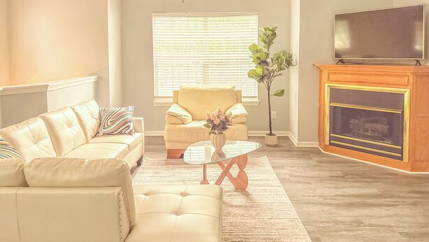 A living room with a sofa, armchair, coffee table, and fireplace.