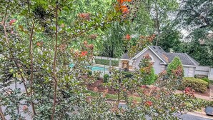 A residential area with a house, a swimming pool, and lush greenery.