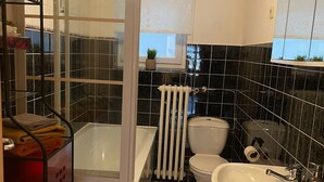 Une salle de bain avec douche, toilettes, lavabo et carrelage au sol.