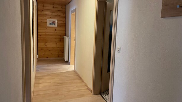 Un couloir aux murs en bois, avec un radiateur et une porte.