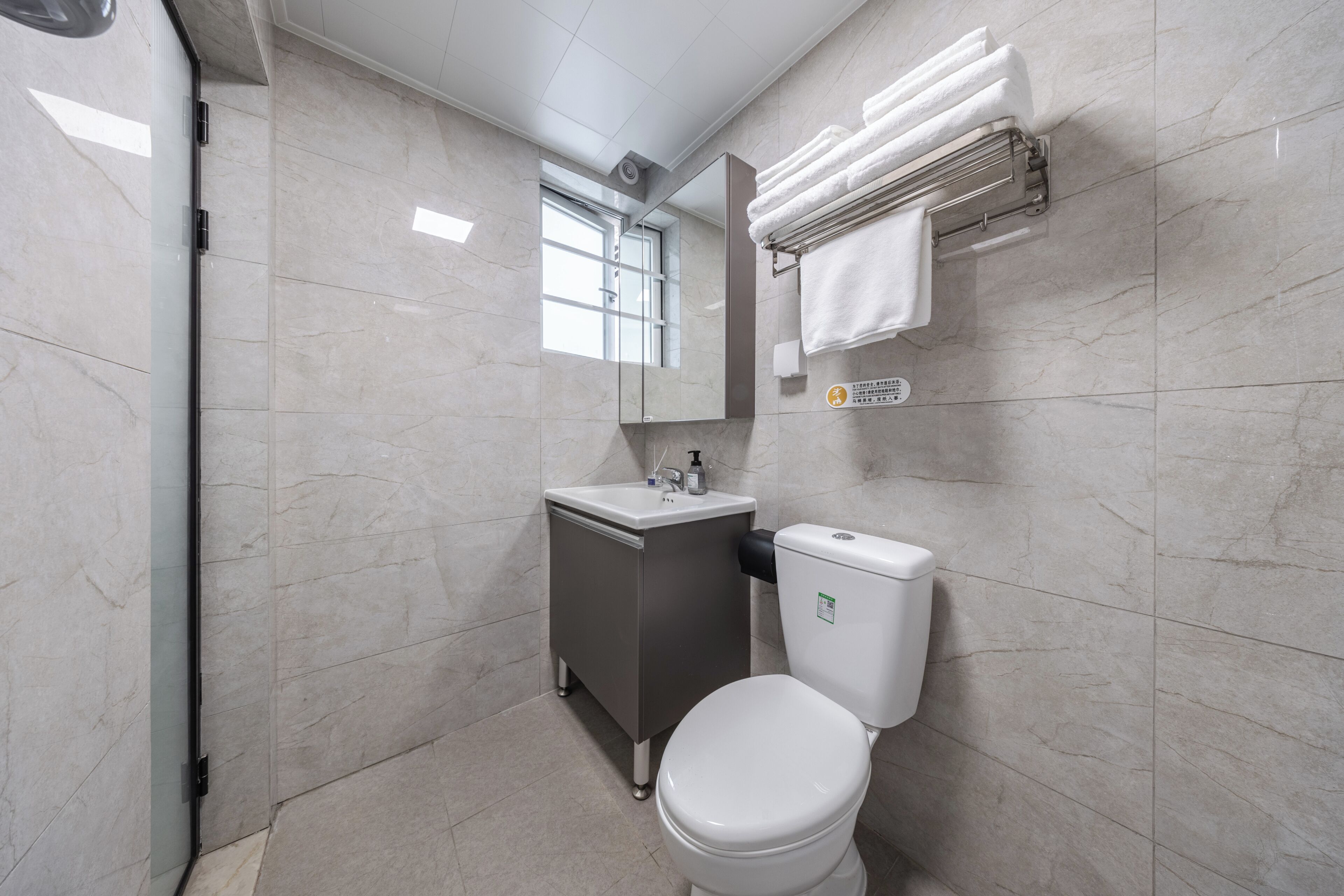 A modern bathroom with a toilet, sink, mirror, and towel rack.
