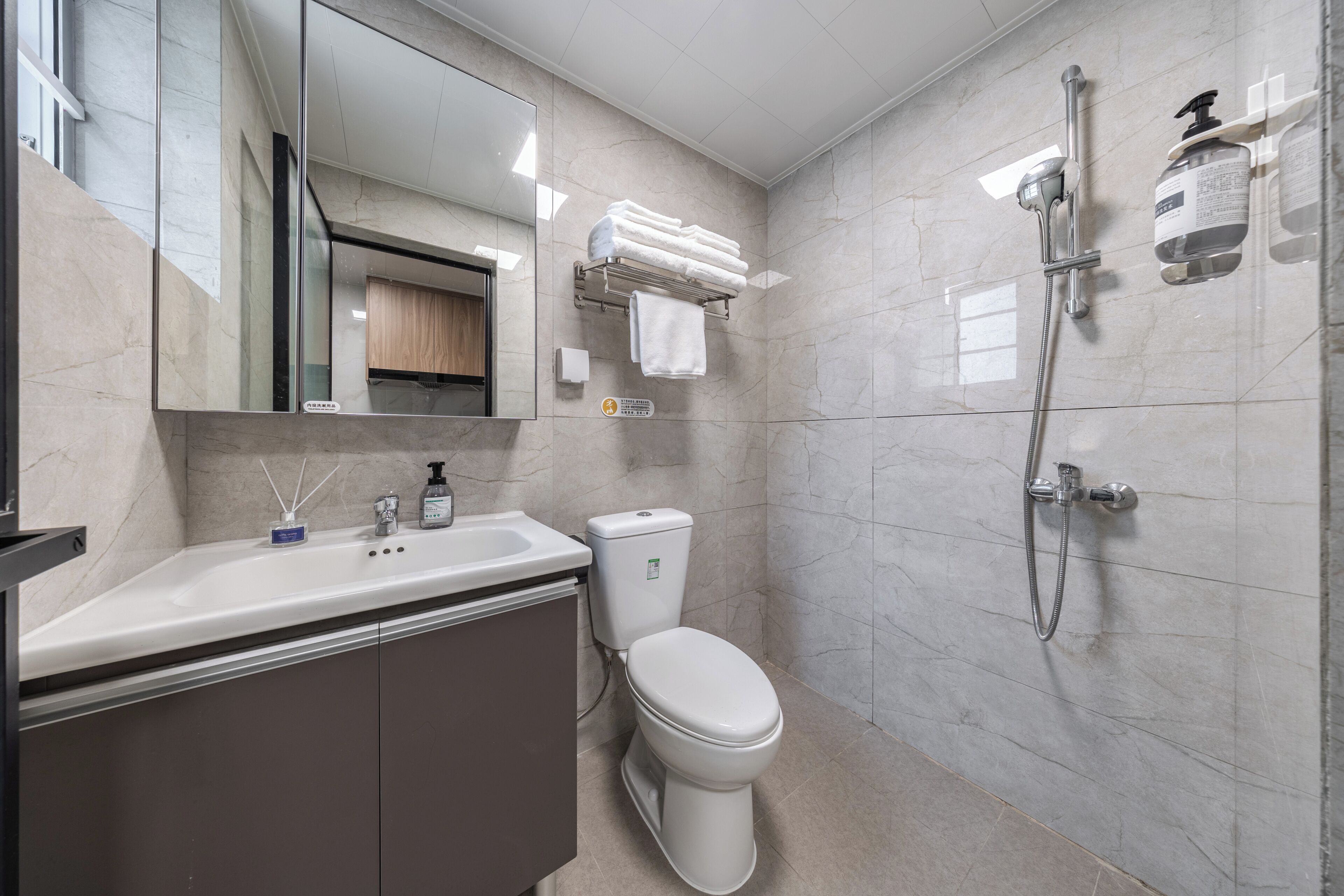 Une salle de bain moderne équipée d’un lavabo, de toilettes et d’une douche.