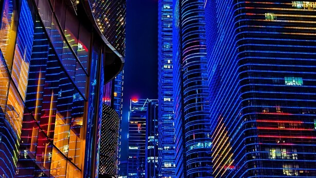 A nighttime cityscape with illuminated skyscrapers and a prominent curved building. - Bailai audio & video yaju (Shenzhen)