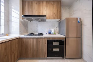 Una cuina moderna amb armaris de fusta, una campana extractora d'acer inoxidable, un rentaplats integrat i un frigorífic beix.