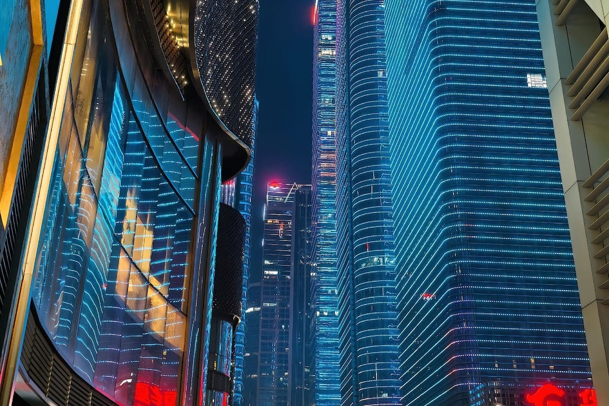 A nighttime cityscape with illuminated skyscrapers and modern architecture.