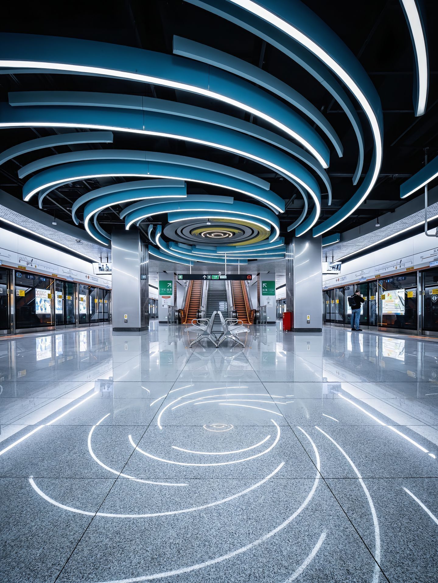 Un espacio interior moderno con una escalera mecánica central, luces de techo curvas y un suelo pulido.