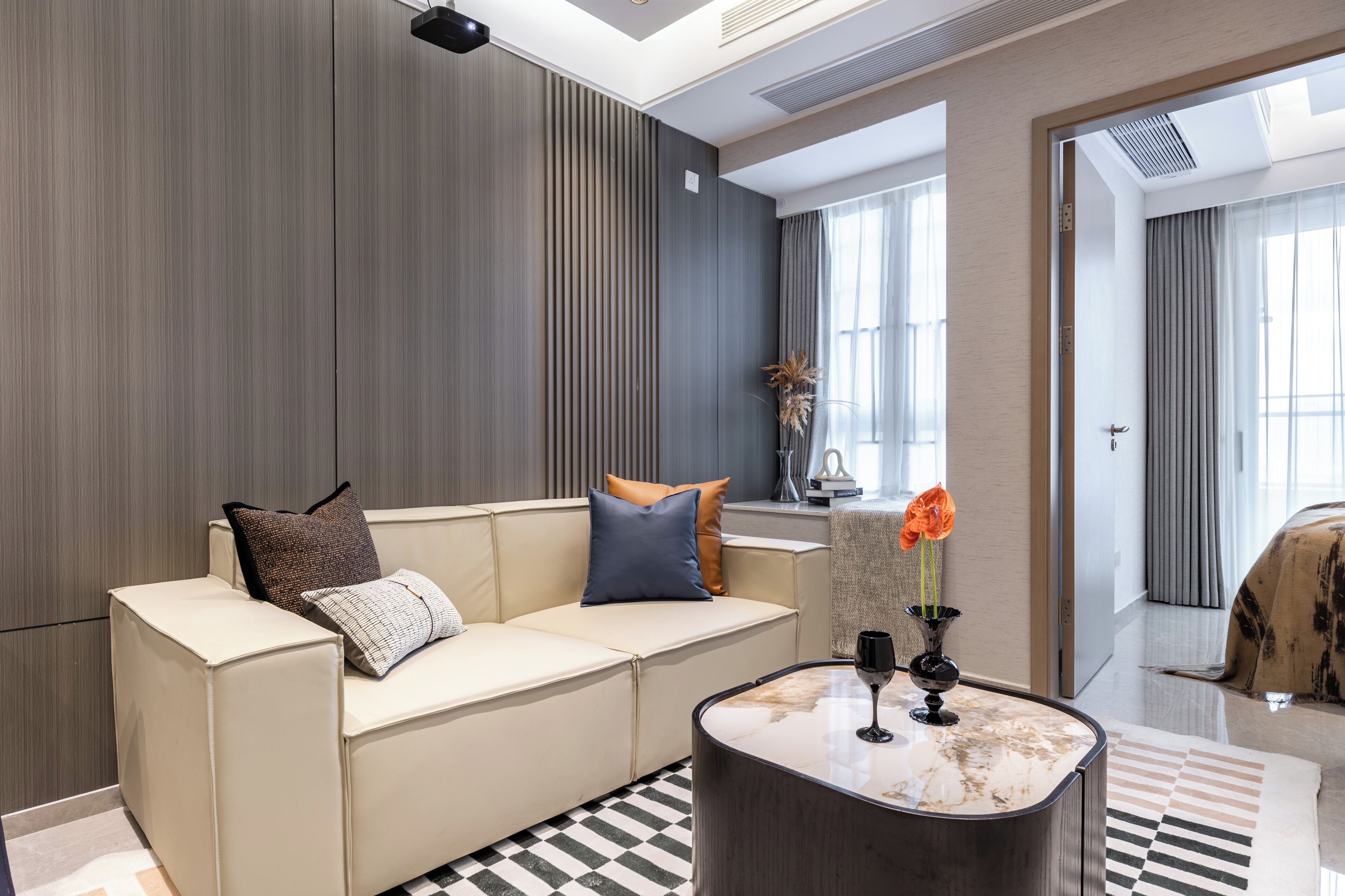 Una sala de estar moderna con un sofá color beige, una mesa de centro de mármol y un suelo a cuadros.