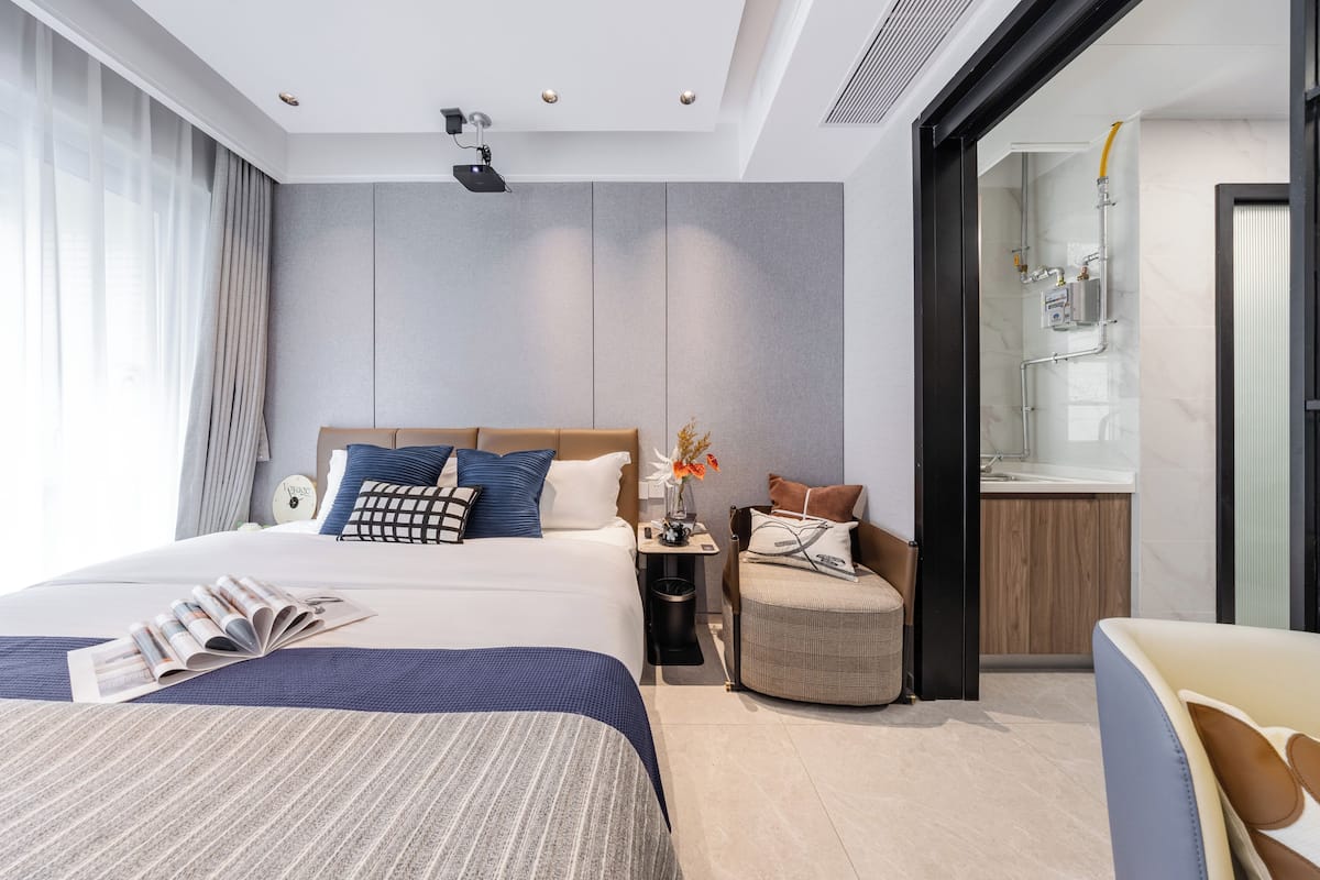 Moderni hotellihuone, jossa on suuri sänky, yöpöytä ja pieni oleskelualue.